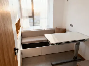 Przytulne miejsce do pracy na niskim poddaszu z drewnianą zabudową pod skosami i jasnym, skandynawskim wystrojem.