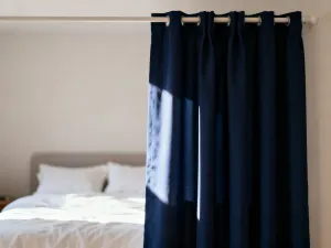 Lniane i bawełniane zasłony w słonecznym salonie, prezentujące różnice w fakturze i przepuszczalności światła tkanin.